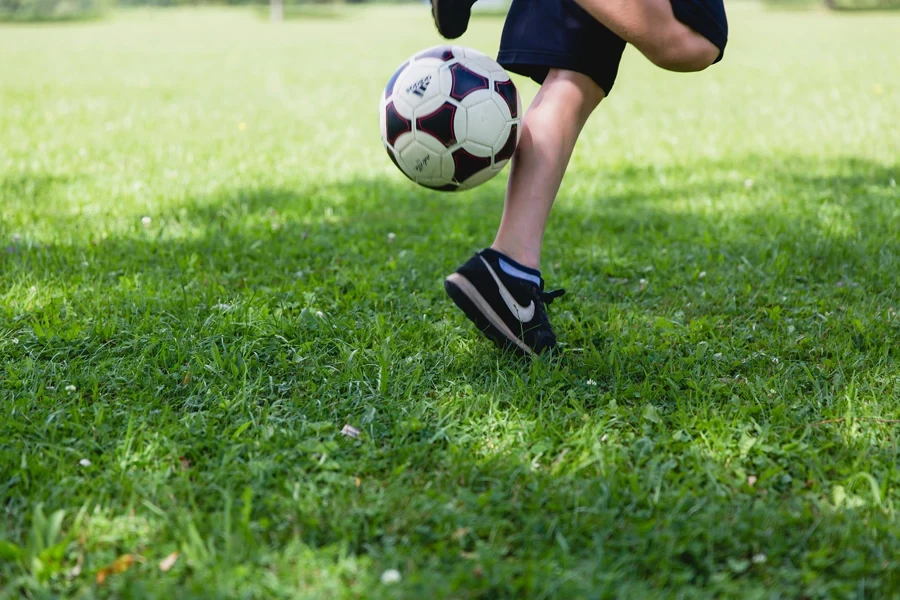 A child skillfully kicks a soccer ball on a sunny day, showcasing outdoor activity and fun