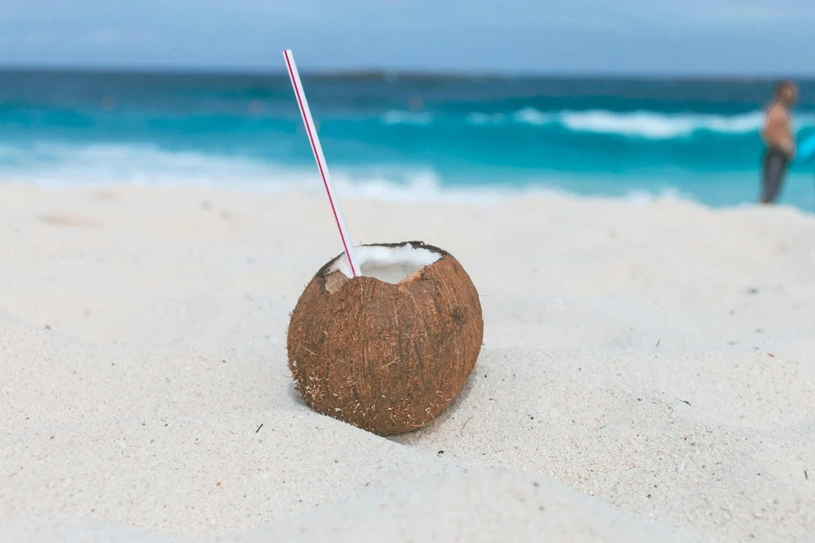 A coconut with a straw in the sand