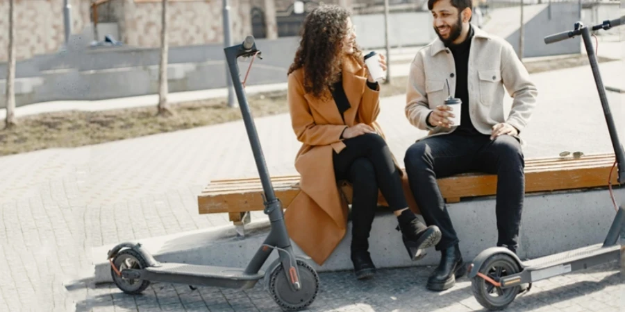A couple enjoying a break outdoors with electric scooters and drinks, exuding joy and companionship