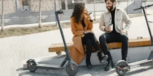 A couple enjoying a break outdoors with electric scooters and drinks, exuding joy and companionship