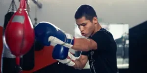 A determined boxer trains with a punching bag in a boxing gym, wearing gloves and sportswear