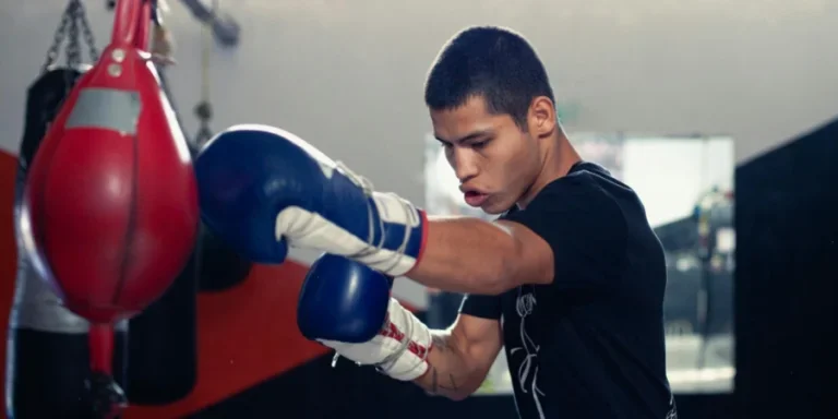 A determined boxer trains with a punching bag in a boxing gym, wearing gloves and sportswear