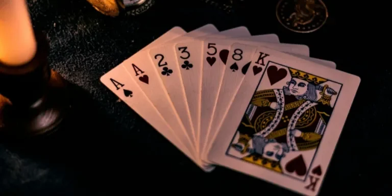 A dimly lit close-up of playing cards with a pocket watch, showcasing a nostalgic casino vibe