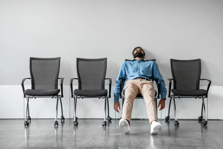 A disappointed man sitting on a row of chairs