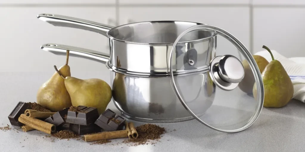 A double boiler next to chocolate and fruits