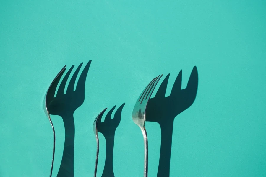 A group of forks casting shadow on a green background