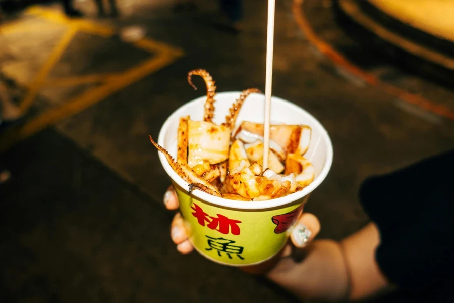 A hand holding a cup of food