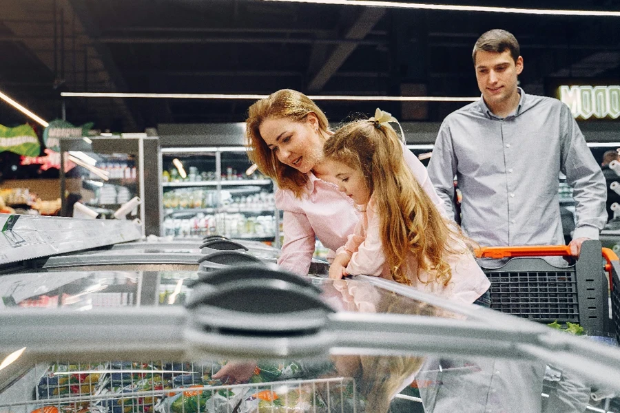 A happy family shopping in the supermarket's freezer section