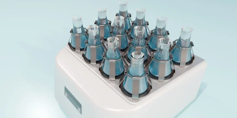 Лабораторный орбитальный шейкер с несколькими колбами, закрепленными на месте зажимами.