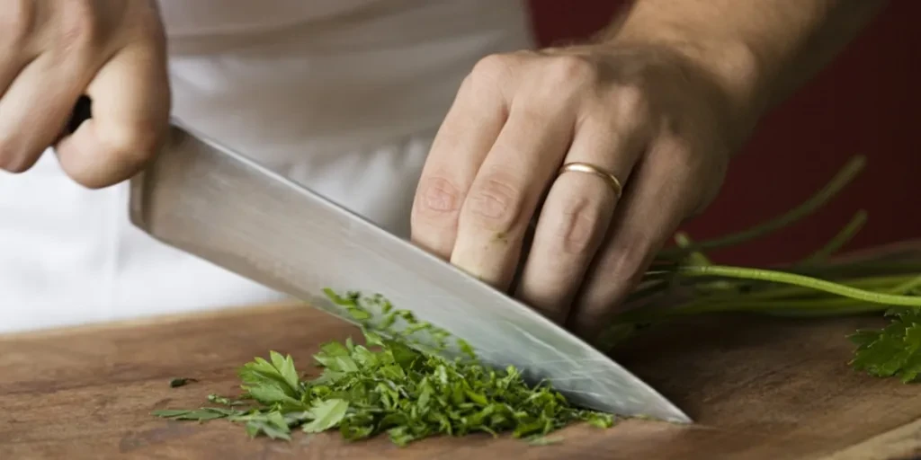 A man using a chef’s knife to cut vegetables