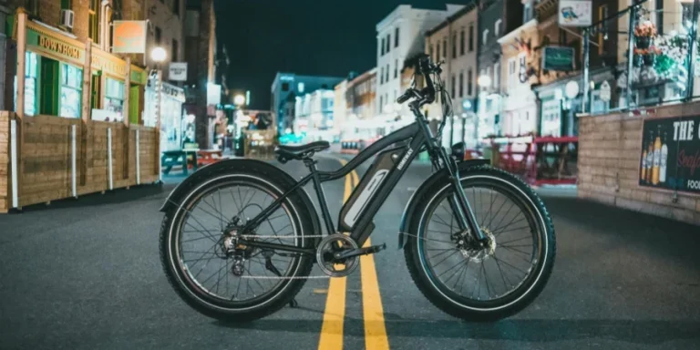 A modern electric bicycle stands on a vibrant city street at night, capturing urban nightlife with colorful lights and architecture