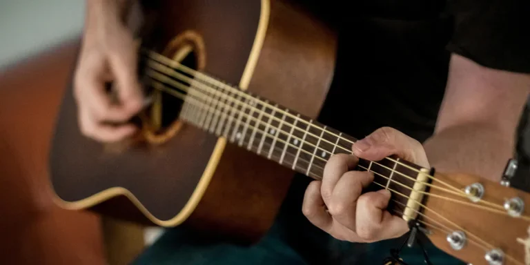 A musician strums chords on an acoustic guitar, showcasing musical talent