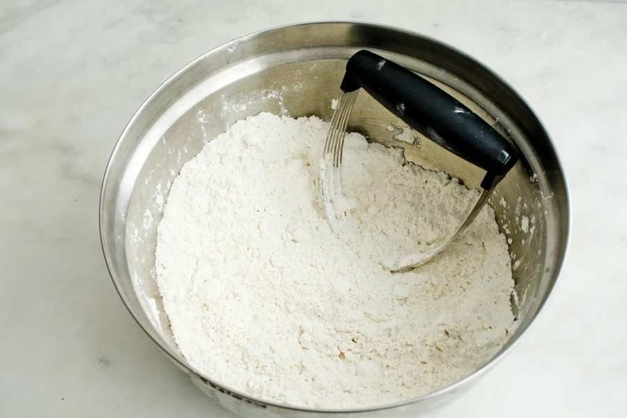 A pastry blender in a bowl of flour