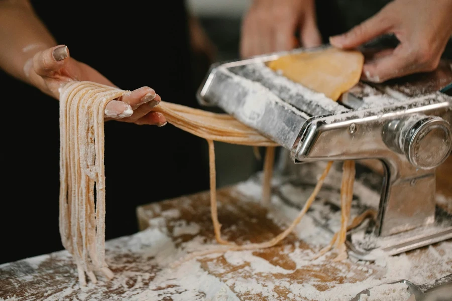 A person making pasta with a machine