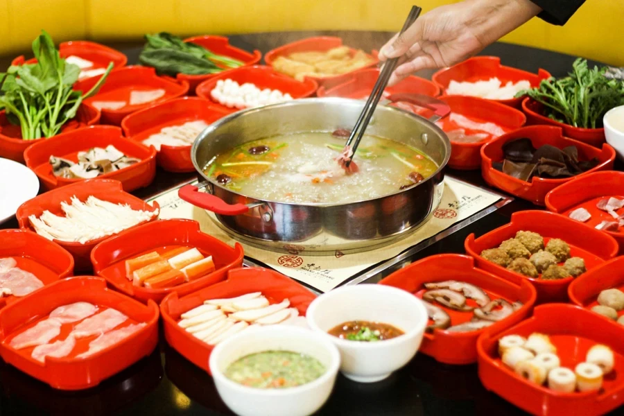 A person stirring a soup in a pot with chopsticks