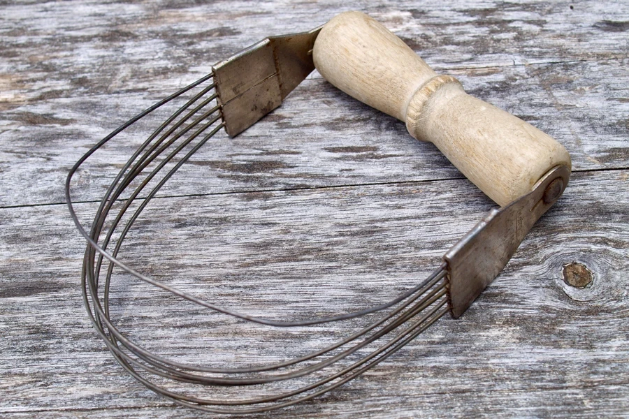 A vintage pastry blender on a wooden surface