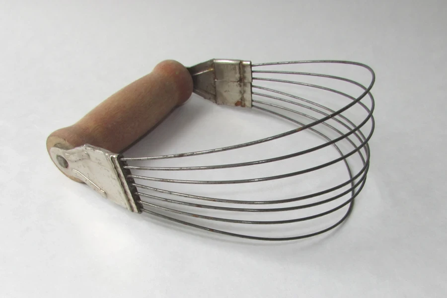 A wired pastry blender on a gray background