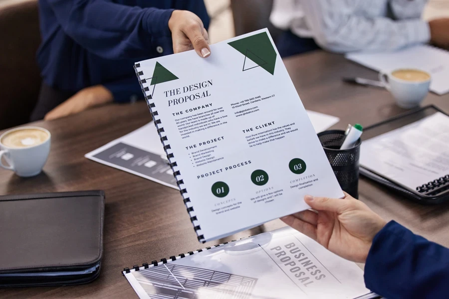 A woman handing over a document proposal in a meeting for creative collaboration
