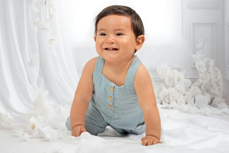 Adorable Baby in Blue Playsuit Smiling Indoors