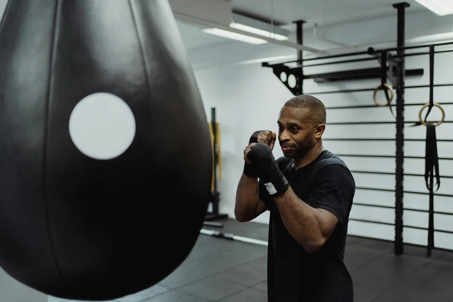 Athletic man practicing boxing in gym with a punching bag and equipment