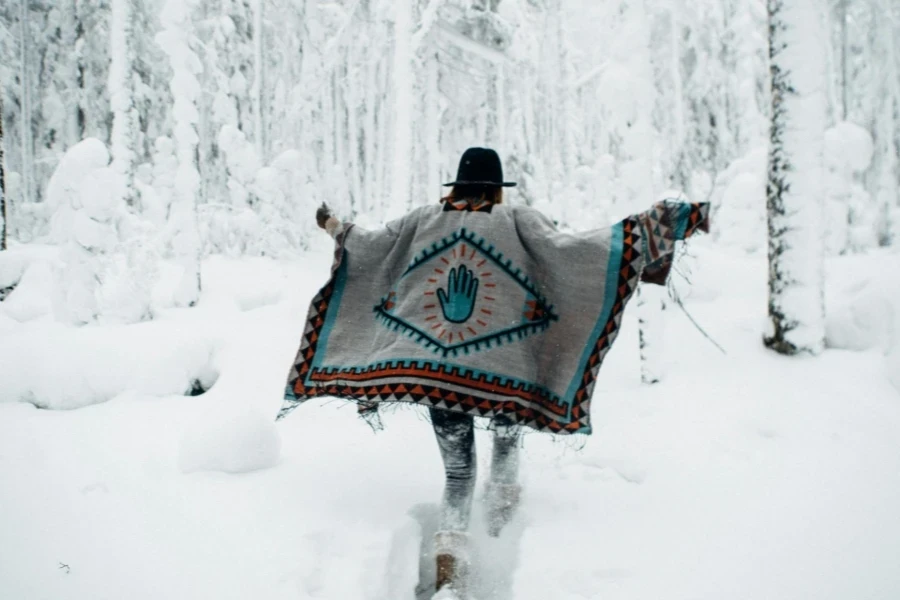 Back View of a Woman in a Poncho Running in a Snowy Forest