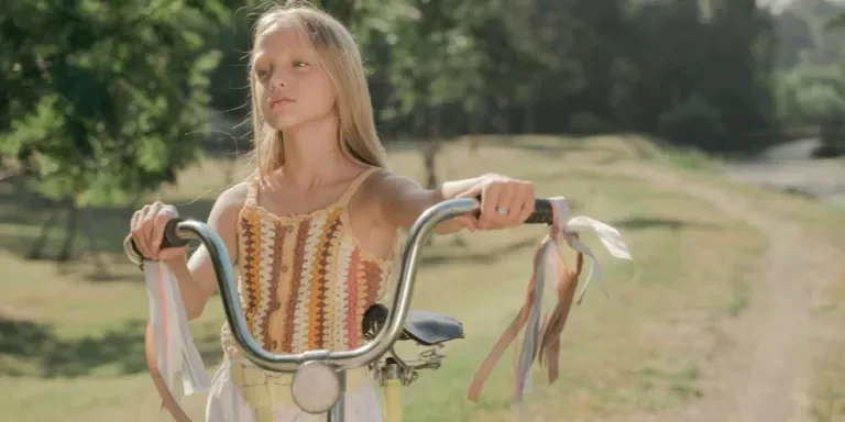 Blonde girl enjoys a sunny day riding a bicycle in a lush green park