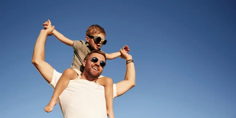 Blue sky, imagination of piloting. Father and son wearing chic sunglasses are together on the field