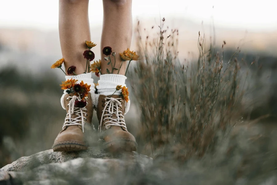 Brown boots adorned with vibrant wildflowers in a natural setting, showcasing a blend of nature and fashion