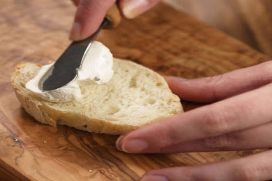 Butter knife from cutlery set spreading cream cheese with ease