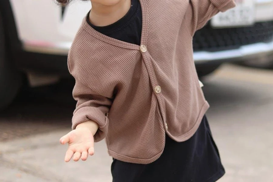 Charming child in a cozy tan lightweight cardigan