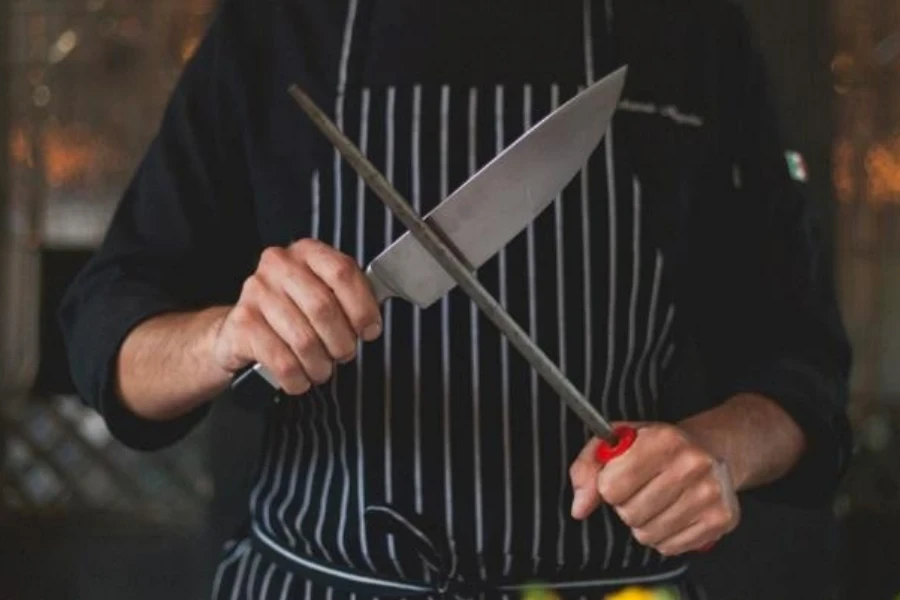 Chef sharpening a knife on a honing rod