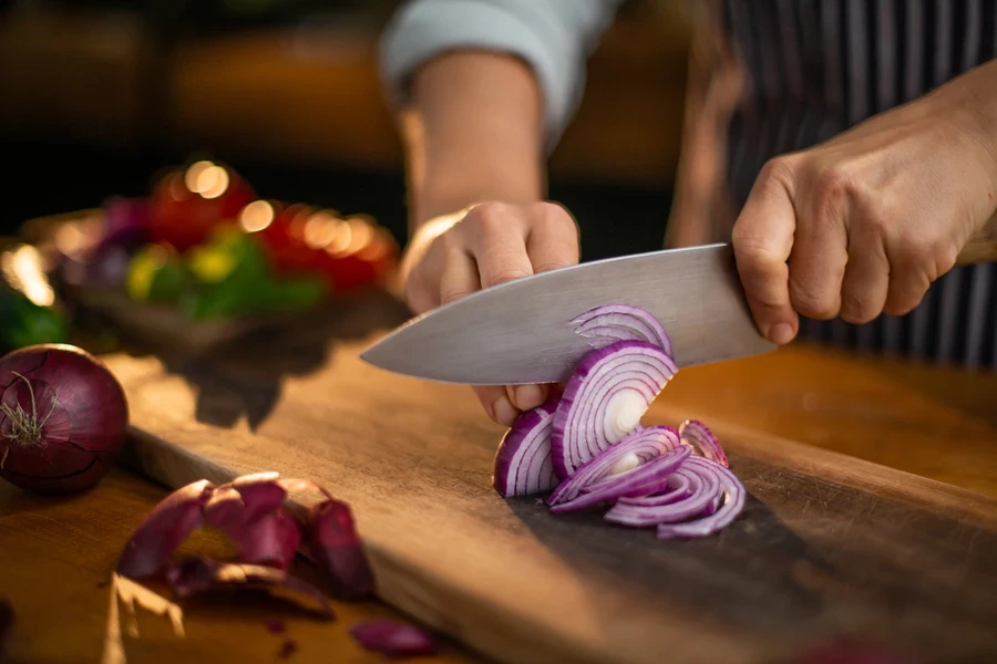Close-up of a chef’s knife cutting onions