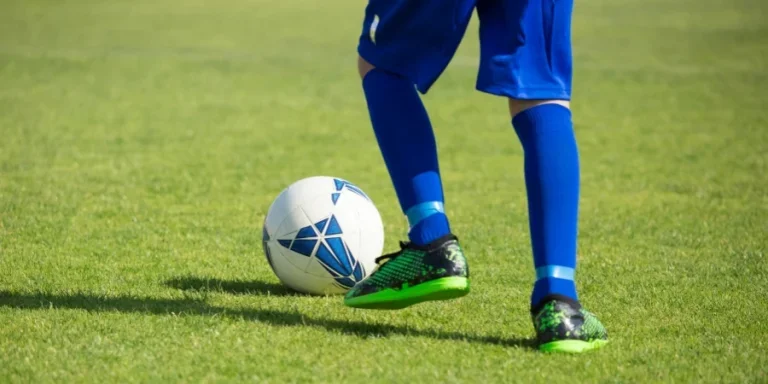 Close-up of a soccer player dribbling a ball on a vibrant green field in Portugal