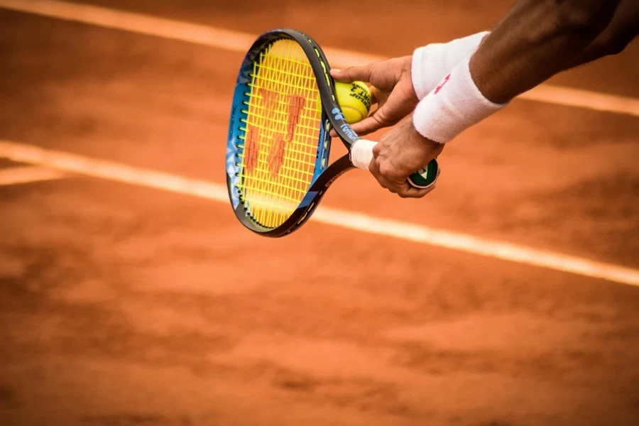 Close-up of a tennis player preparing to serve on a clay court in Montevideo