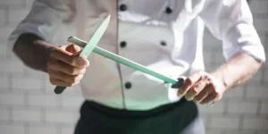 Koch schärft Messer auf Wetzstahl