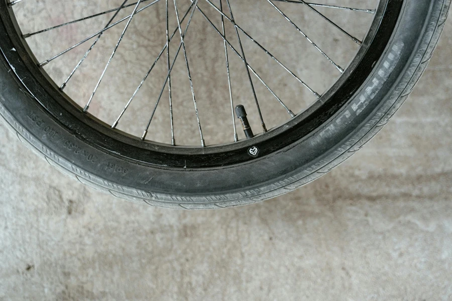 Detailed close-up of a bicycle wheel showing the spokes and valve on a concrete surface