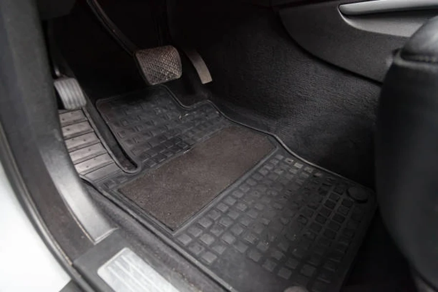 Dirty grey carpet, accelerator and brake car floor mats in car maintenance workshop before dry cleaning.