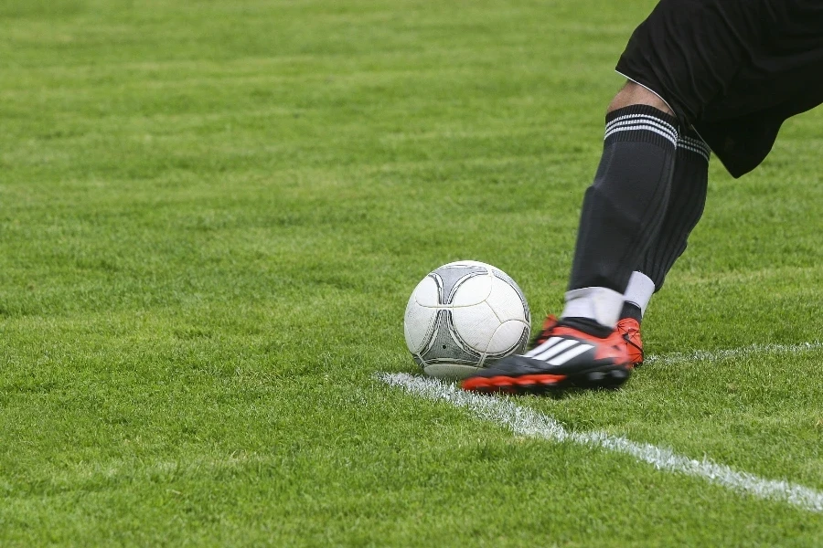 Dynamic shot of a soccer player kicking the ball on a grassy field, showcasing fast-paced sports action