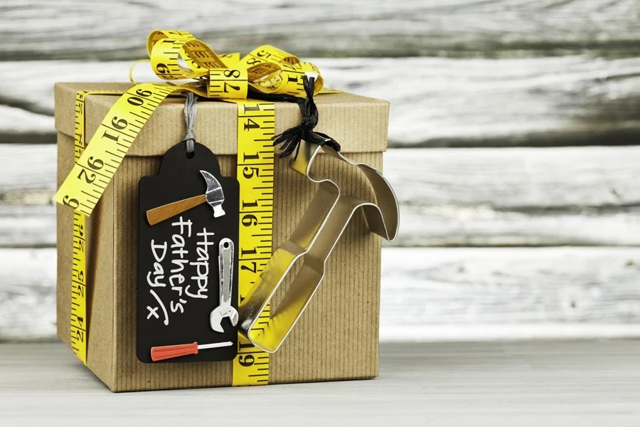 Father's Day gift for the DIY dad. Gift decorated with tape measure DIY gift tag and metal hammer shape. Shot against rustic wooden background
