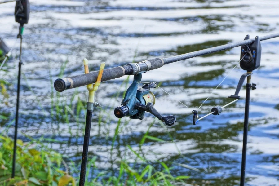Fishing tackle with fishing rod and reel near the water on the shore