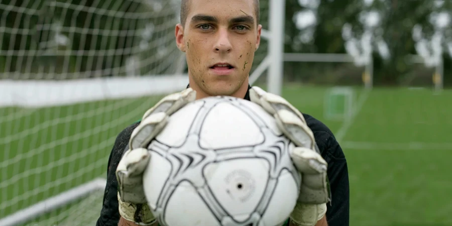 Focused soccer goalkeeper holding the ball confidently on the field