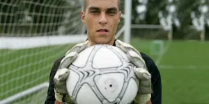 Focused soccer goalkeeper holding the ball confidently on the field