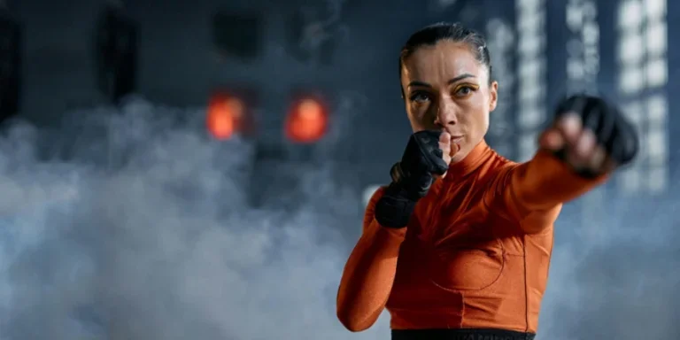 Сосредоточенная женщина в спортивной одежде занимается боксом