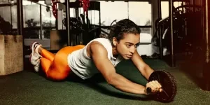 Focused woman using ab roller to workout in a contemporary gym setting