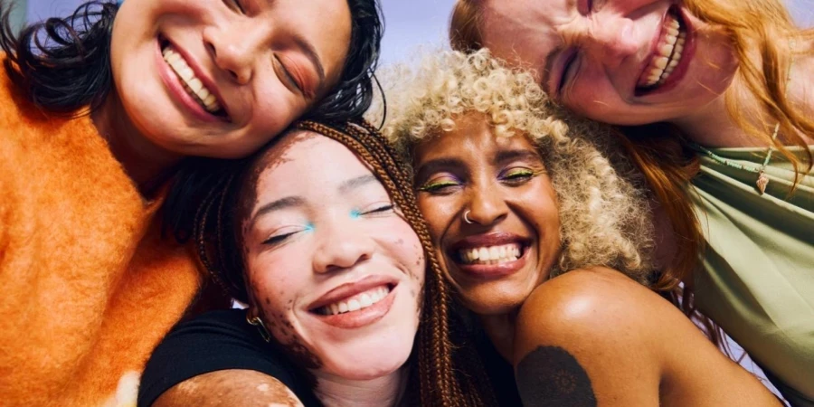 Four diverse Gen Z women embracing and smiling with eyes closed