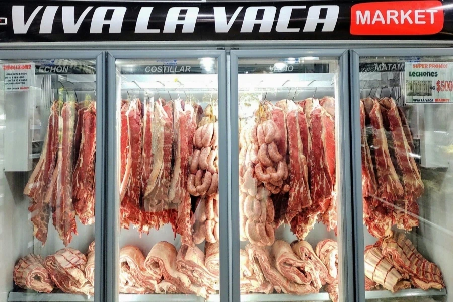 Fresh cuts of meat and sausages in a well-lit market refrigerator display