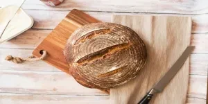 Fresh loaf of bread on cutting board with bread knife