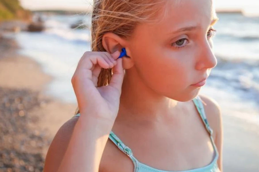 Girl with earplugs in the water on the beach