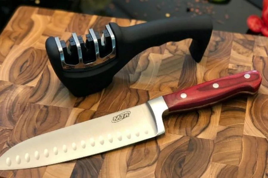 Knife on cutting board next to manual knife sharpener