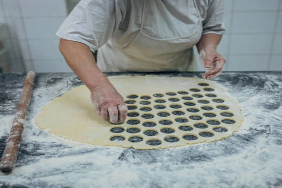 Large pastry dough with chef cutting shapes into it
